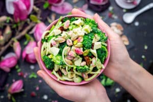 Image of a person holding a bowl of vegan salad with pistachios.