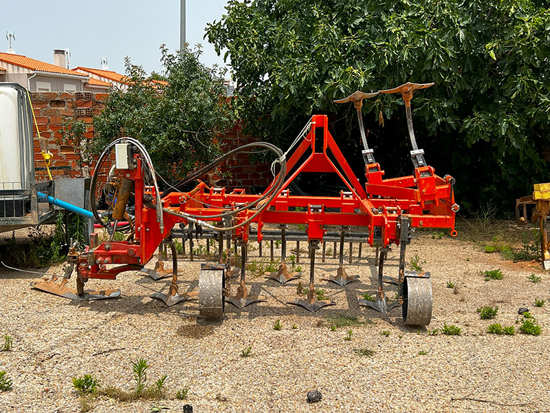 Image d'un outil de travail du sol entre les vignes utilisé pour la culture des pistachiers.